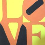 Painting of the word love in yellow, black, and orange