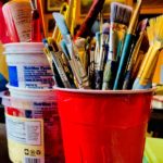 a red plastic with paint brushes of various sizes